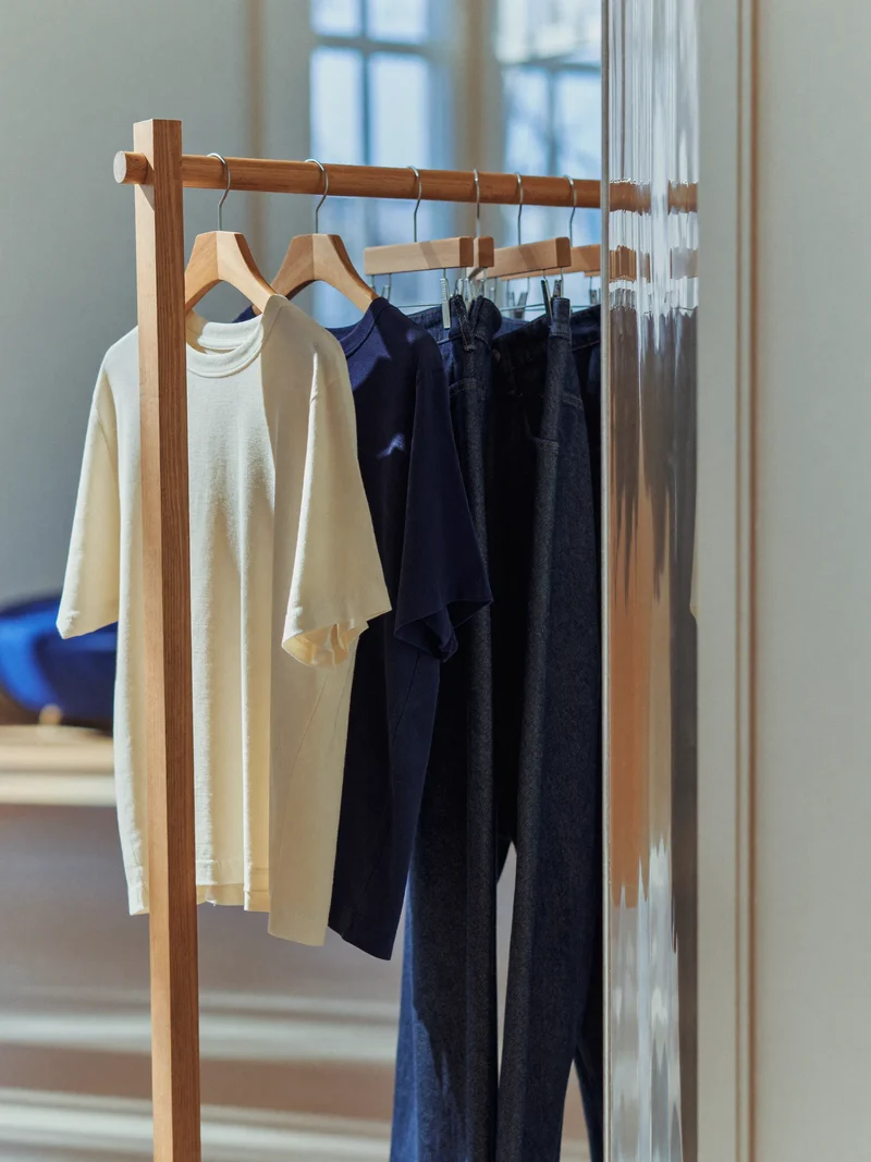 Holzkleiderstange mit Kleinkind-Shirts und Jeanslatzhosen in hellem Ladeneck